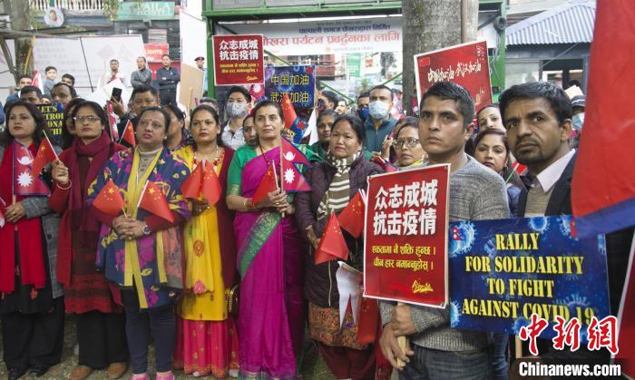 参加活动的当地民众举着“众志成城，抗击疫情”等标牌。　詹晖林 摄