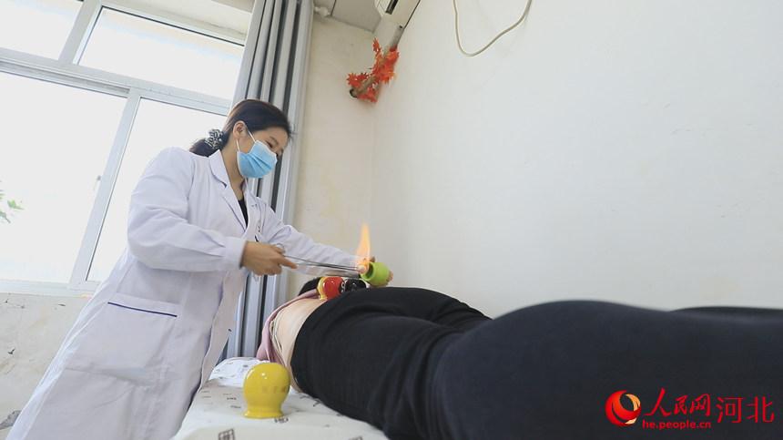 医生正在用拔火罐疗法为患者治疗肩胛疼痛，背部沉重。 孙海峰摄